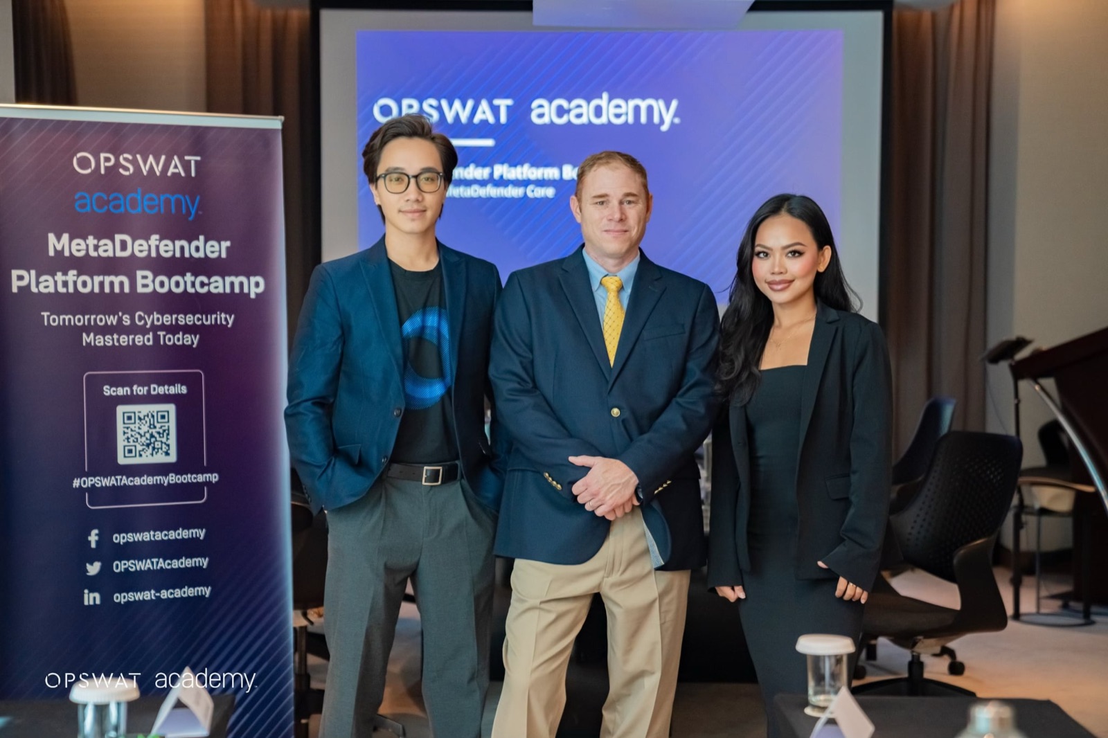 Duy with two colleagues in front of the OPSWAT Academy bootcamp banner
